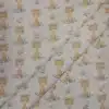 Tela de algodón estampada con jirafas sobre fondo claro, acompañadas de pequeñas hojas, ramas y motivos vegetales en tonos suaves.