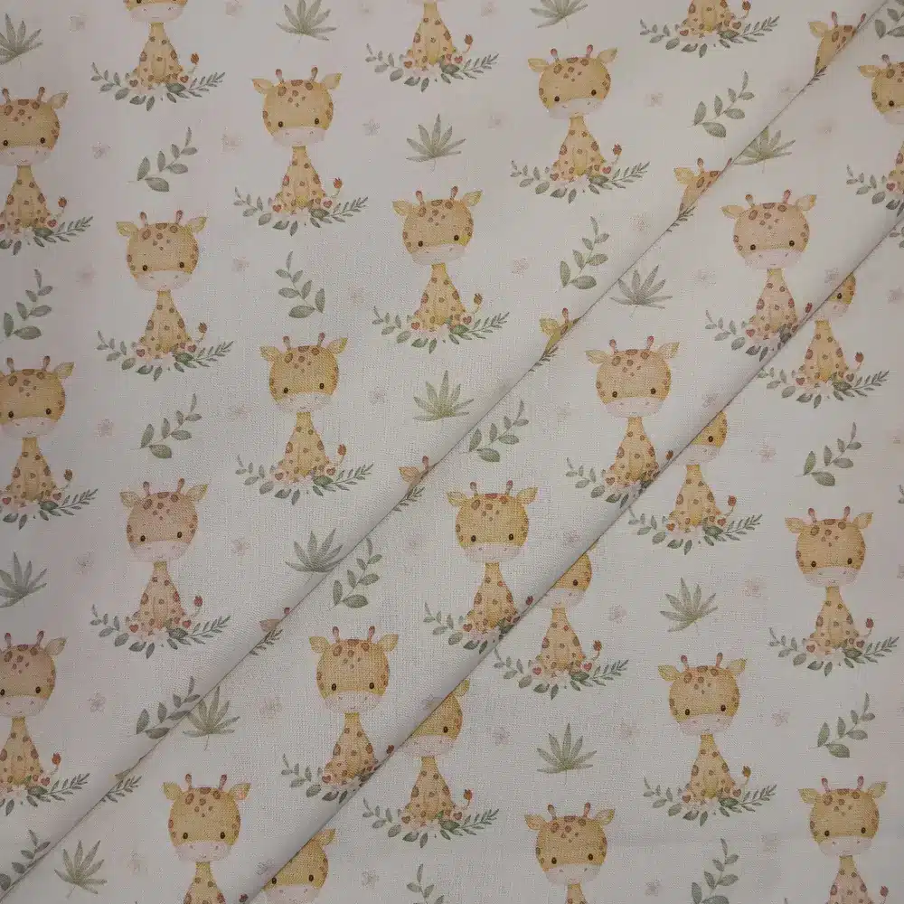 Tela de algodón estampada con jirafas sobre fondo claro, acompañadas de pequeñas hojas, ramas y motivos vegetales en tonos suaves.