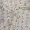 Tela de algodón estampada con jirafas sobre fondo claro, acompañadas de pequeñas hojas, ramas y motivos vegetales en tonos suaves.