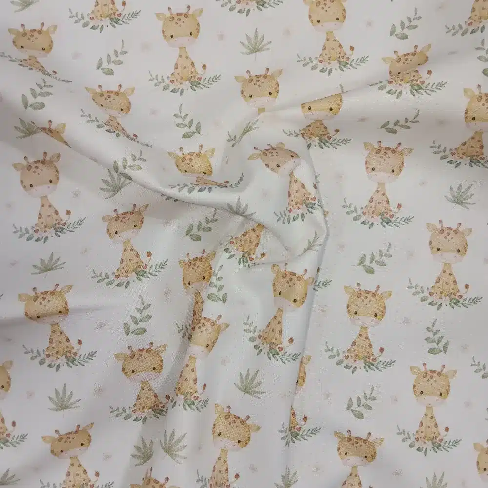 Tela de algodón estampada con jirafas sobre fondo claro, acompañadas de pequeñas hojas, ramas y motivos vegetales en tonos suaves.