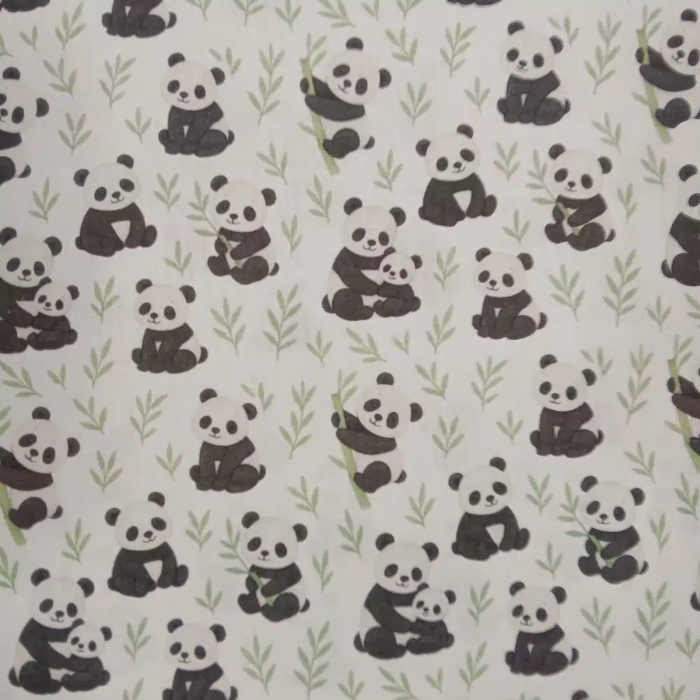 Tela de algodón estampada con osos panda sobre fondo claro, con pandas en diferentes posturas, pequeñas ramas verdes y motivos de bambú.