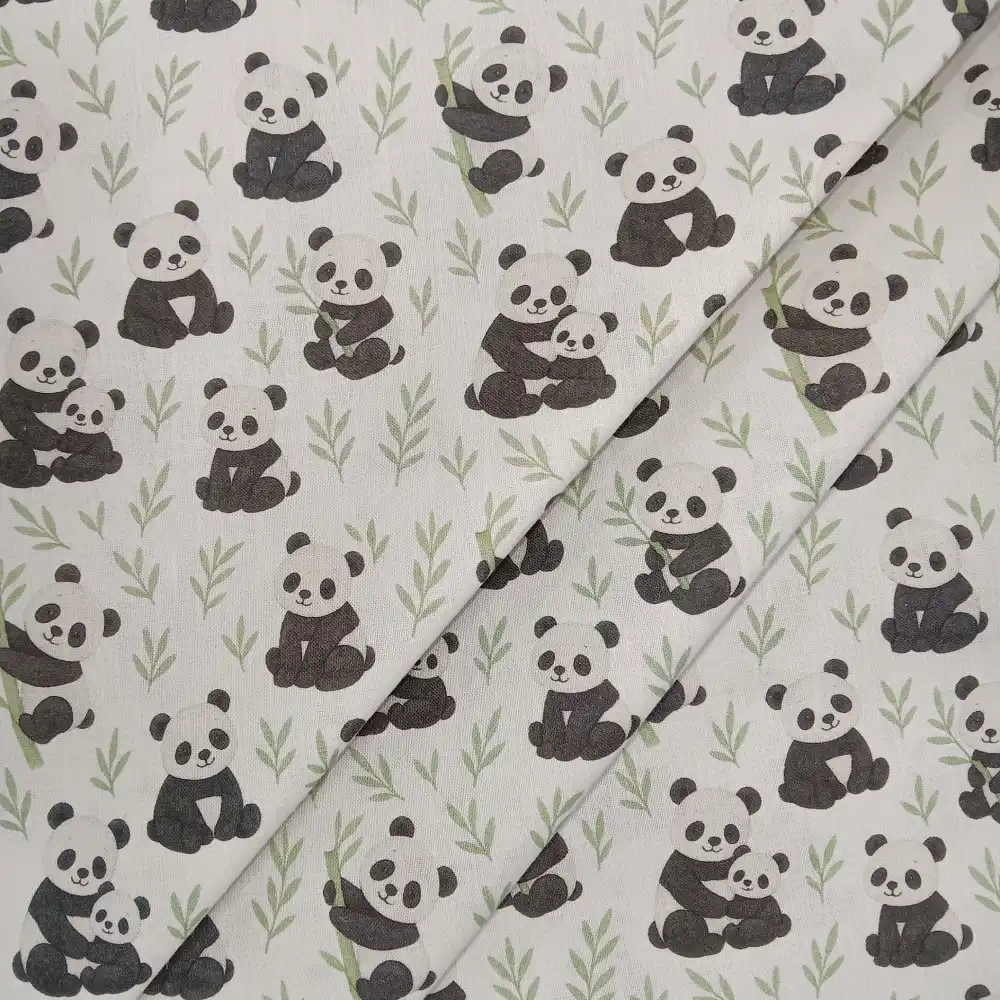 Tela de algodón estampada con osos panda sobre fondo claro, con pandas en diferentes posturas, pequeñas ramas verdes y motivos de bambú.