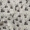 Tela de algodón estampada con osos panda sobre fondo claro, con pandas en diferentes posturas, pequeñas ramas verdes y motivos de bambú.