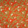 Tela de algodón naranja con flores beige de centros oscuros y ramas de hojas verdes alargadas, distribuidas sobre un fondo naranja intenso.