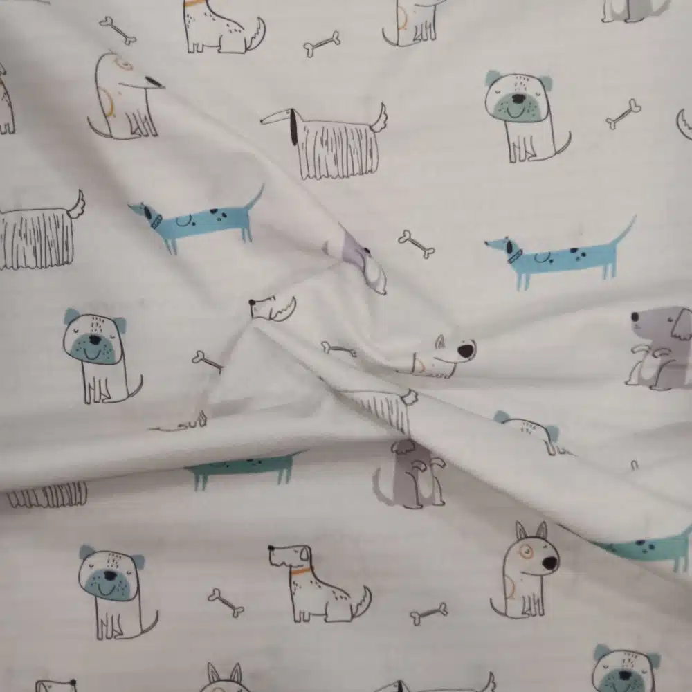 Tela de algodón estampada con perros divertidos de diferentes diseños y pequeños huesos en tonos suaves sobre fondo claro.