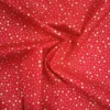 Tela de algodón navideña roja con numerosas estrellas doradas de diferentes tamaños distribuidas por toda la superficie.