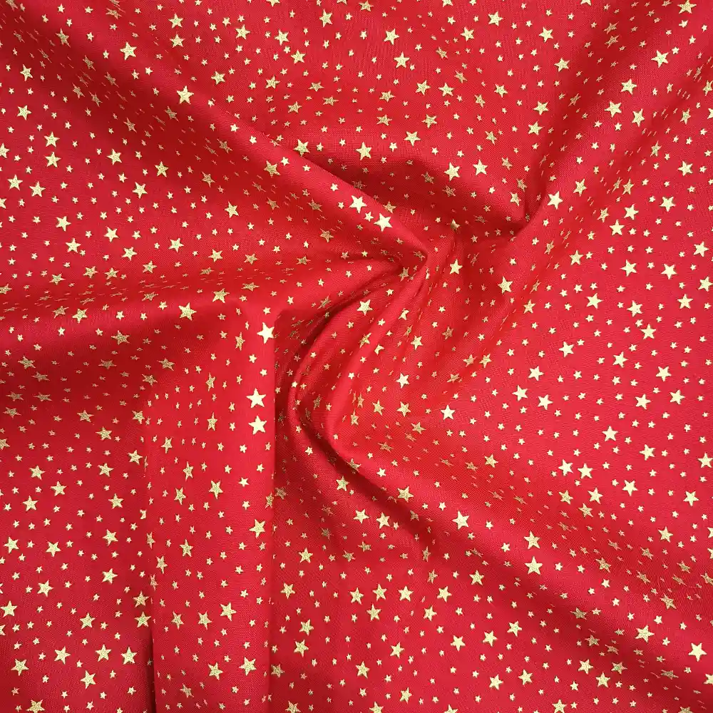 Tela de algodón navideña roja con numerosas estrellas doradas de diferentes tamaños distribuidas por toda la superficie.