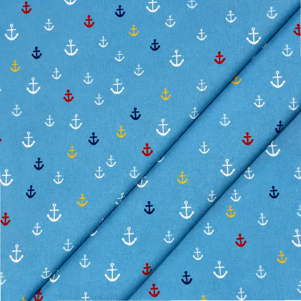 Tela de algodón azul con pequeñas anclas estampadas de diferentes tamaños en blanco, rojo, amarillo y azul marino, distribuidas por toda la superficie.