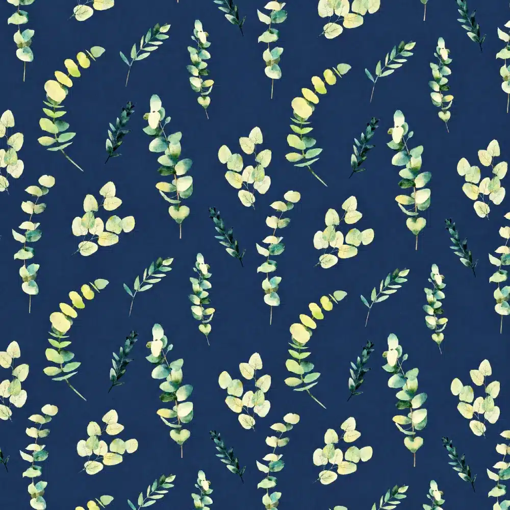 Tela de algodón azul oscuro con estampado de ramas y hojas de eucalipto en diferentes tonos verdes, amarillos suaves y crema, distribuidas sobre el fondo.