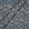 Tela de algodón azul petróleo con flores beige y estampado botánico, presentada con varios pliegues diagonales.