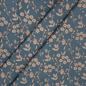Tela de algodón azul petróleo con flores beige y estampado botánico, presentada con varios pliegues diagonales.