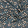 Tela de algodón azul petróleo con flores beige y hojas, recogida en pliegues alrededor del centro.