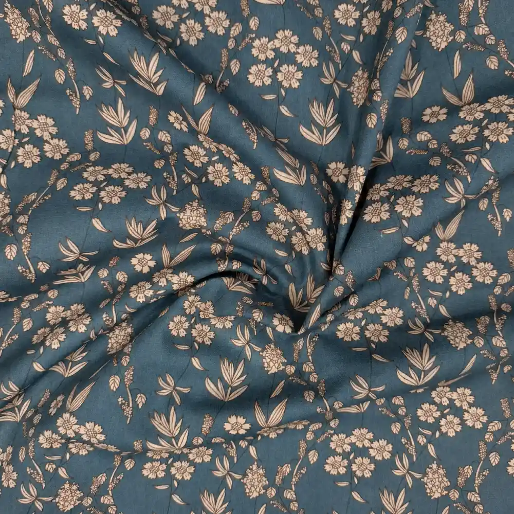 Tela de algodón azul petróleo con flores beige y hojas, recogida en pliegues alrededor del centro.