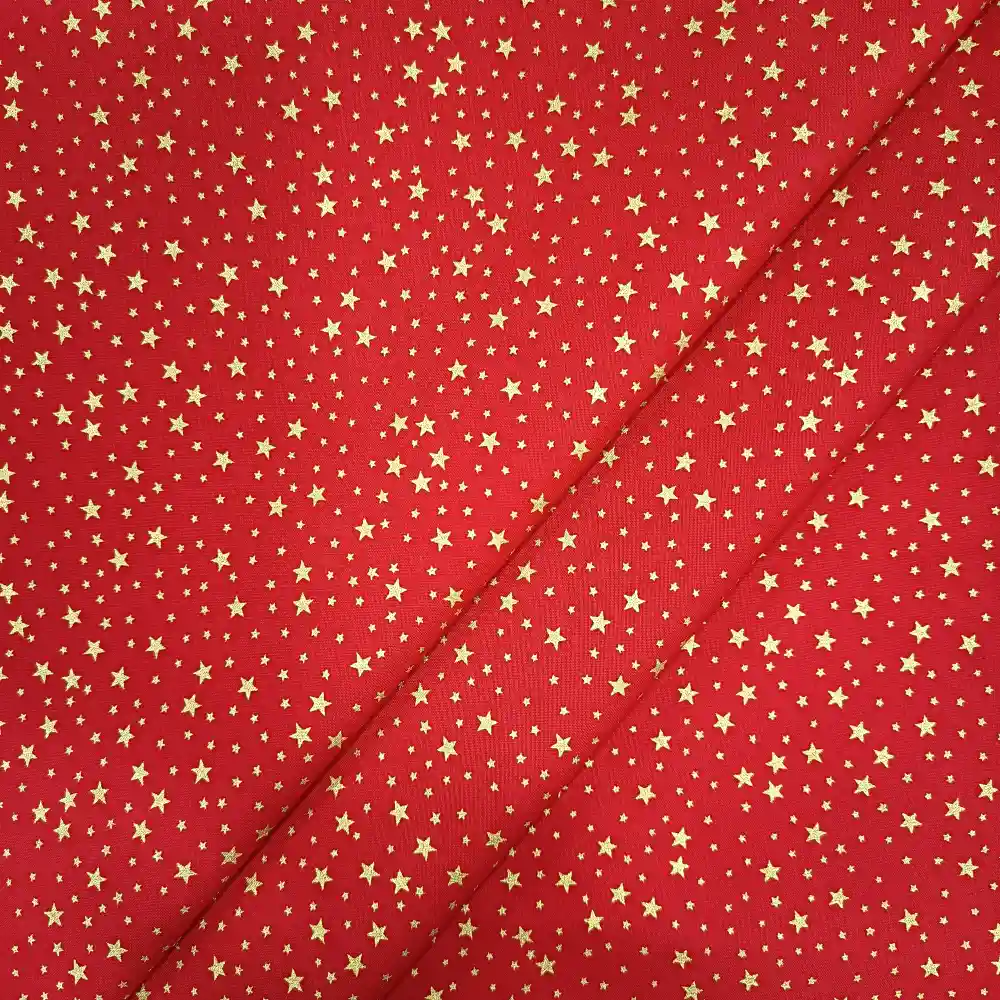 Tela de algodón navideña roja con numerosas estrellas doradas de diferentes tamaños distribuidas por toda la superficie.