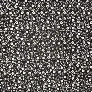 Tela de algodón negra con flores blancas pequeñas, ramas finas y hojas distribuidas sobre el fondo negro.
