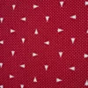 Detalle de tela jacquard roja con pequeños árboles de Navidad blancos orientados en distintas direcciones y diminutos motivos blancos repartidos por toda la superficie.