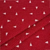 Detalle de tela jacquard roja con pequeños árboles de Navidad blancos orientados en distintas direcciones y diminutos motivos blancos repartidos por toda la superficie.