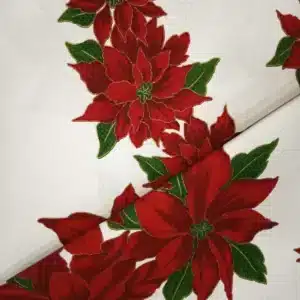 Tela de mantelería navideña blanca con grandes flores de Pascua rojas y burdeos, hojas verdes y finos contornos dorados, sobre fondo blanco con textura.